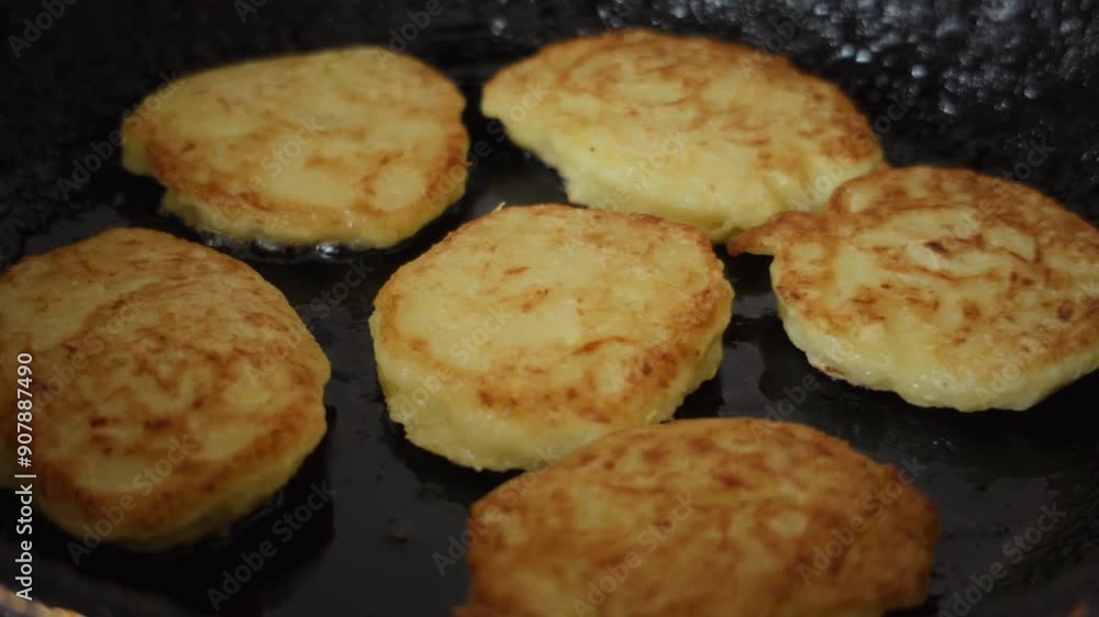 Close-up of golden homemade zucchini fritters sizzling in a frying pan on a stovetop. High quality 4k footage Close-up of golden homemade zucchini fritters sizzling in a frying pan on a stovetop. High quality 4k footage