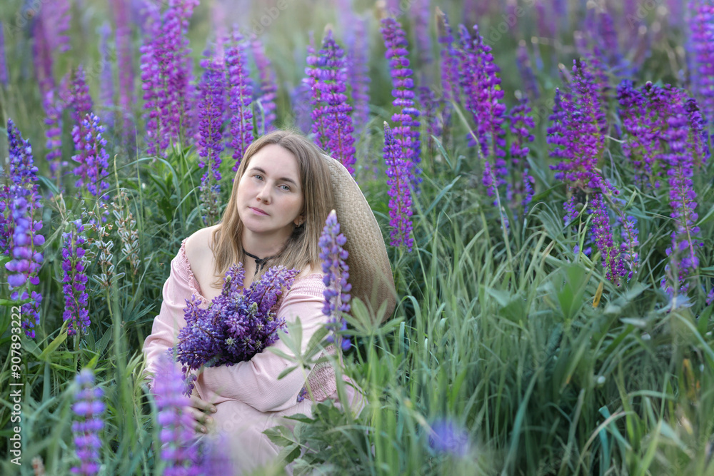 Beautiful girl with londy hair in the summer in a field of blooming purple lupine flowers with a bouquet in her hands Beautiful girl with londy hair in the summer in a field of blooming purple lupine flowers with a bouquet in her hands