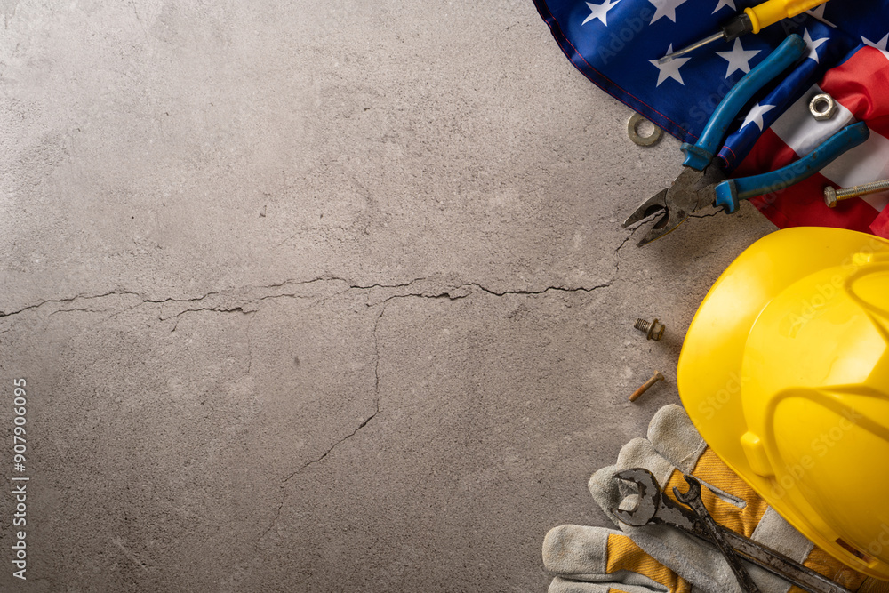 Top view of construction tools, safety helmet, gloves, and USA flag on a concrete surface Top view of construction tools, safety helmet, gloves, and USA flag on a concrete surface
