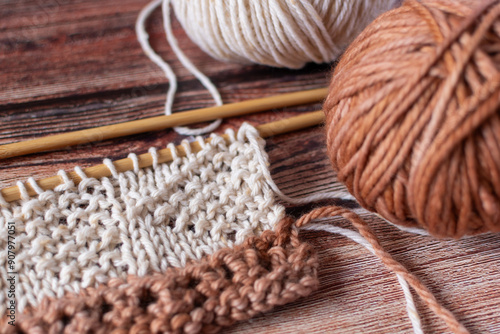 lovely hand knitting on neutral eathy shades of brown and cream - top down knit fabric background - wooden knitting needles  photo