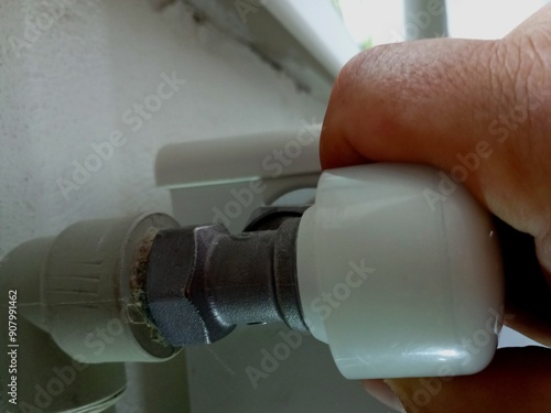 Turning the tap on the heating radiators. The topic of saving heat. A man turns off the heating in the house with his hand. photo