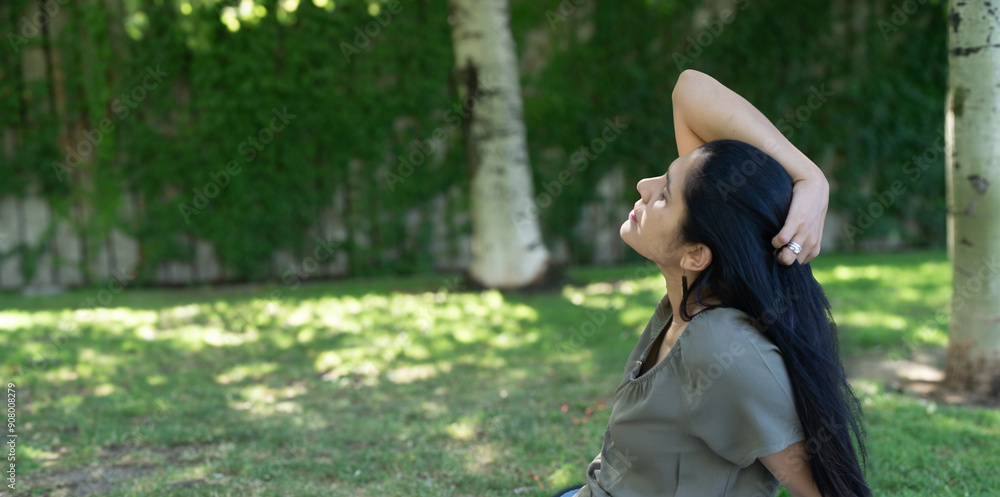 Naklejka premium A woman is sitting in the grass and looking up at the sky