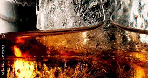 Glass, ice and pour liquid in studio for enjoyment, closeup and cold beverage. Frozen cube, tumbler and whiskey flow on black background with liquor, brandy and aesthetic for testing in distillery