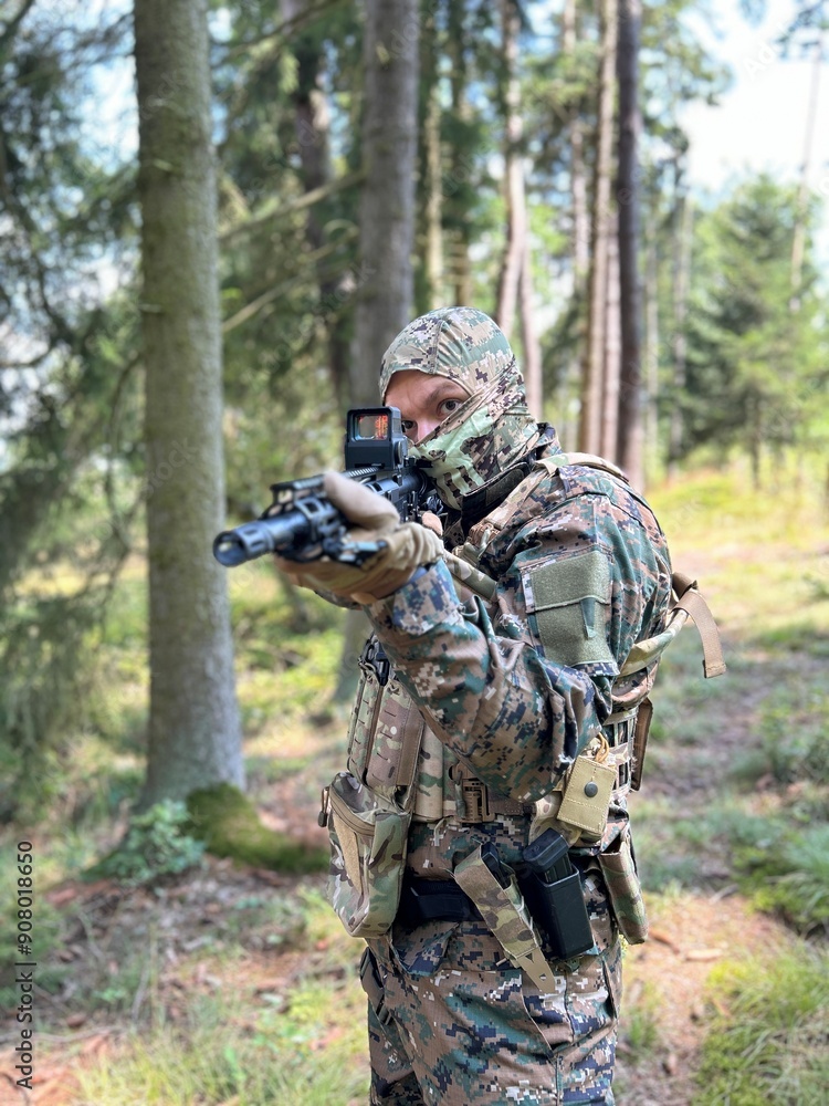 A soldier aiming a rifle. A soldier with a rifle in his hand standing in the forest. Dressed in camouflage. A soldier aiming a rifle. A soldier with a rifle in his hand standing in the forest. Dressed in camouflage.