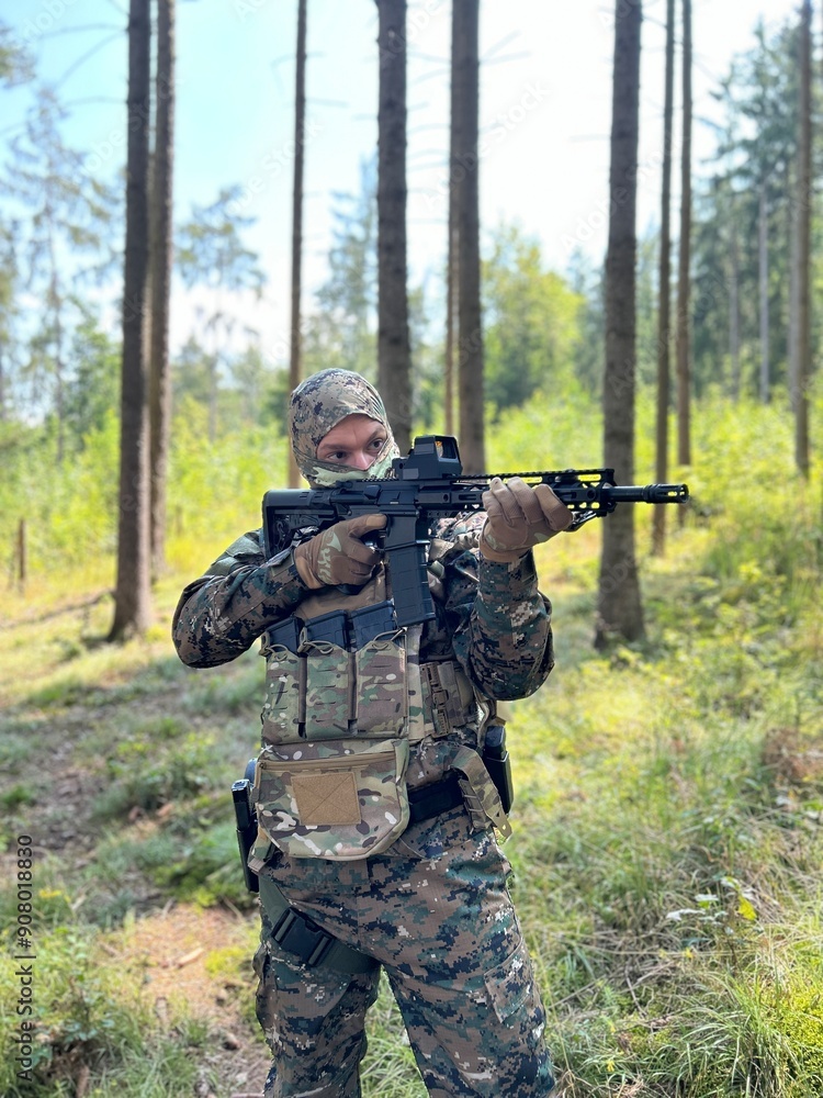 A soldier aiming a rifle. A soldier with a rifle in his hand standing in the forest. Dressed in camouflage. A soldier aiming a rifle. A soldier with a rifle in his hand standing in the forest. Dressed in camouflage.