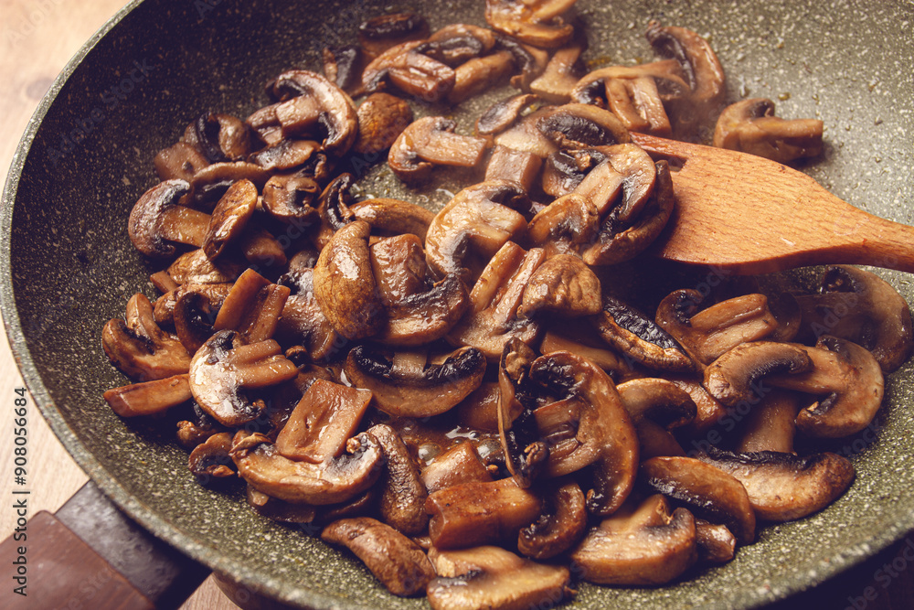 Fototapeta premium fried mushrooms in a frying pan, with a wooden fork, homemade, no people,
