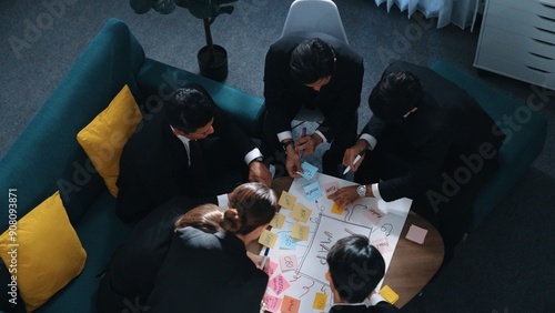 Top view of skilled businesswoman write marketing idea and placed sticky notes on mind mapping while planning financial strategy with diverse business group. Startup team working together. Directorate photo