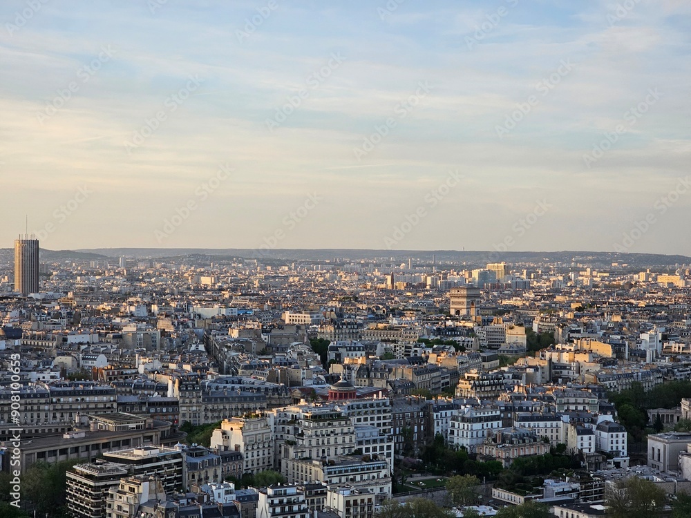 Fototapeta premium Paris, France - April 12, 2024: Aerial view to the city of Paris, during the golden hour between modern skyscrapers and old buildings. Beautiful sunset over the city reflected on the buildings.