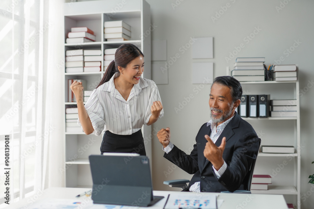Businessman and businesswoman are raising their fists in the air, happy about their success while looking at a tablet Businessman and businesswoman are raising their fists in the air, happy about their success while looking at a tablet