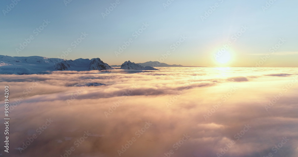 Drone flight over bright colorful clouds during sunset. Golden hour and amazing sun rays in blue sky. Beautiful ocean of fog at sunrise. Sun shines brightly over towering snow covered mountain range Drone flight over bright colorful clouds during sunset. Golden hour and amazing sun rays in blue sky. Beautiful ocean of fog at sunrise. Sun shines brightly over towering snow covered mountain range