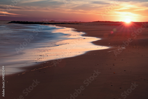 Sunset along Long Island, New York beach with ocean, colorful sky and sand