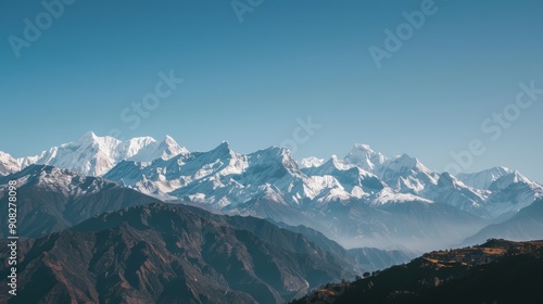 The majestic himalayan mountain range is bathed in sunshine, with its snow-capped peaks piercing the clear blue sky