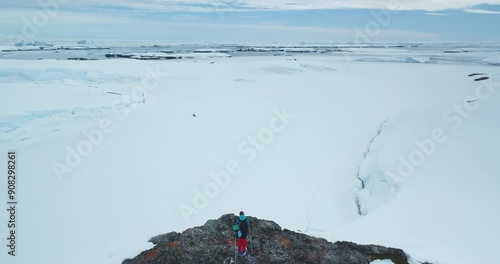 Tourist man skiing Antarctic snow mountain slope nature landscape. Alpine tourism in wild harsh conditions. Winter trekking extreme sport. Antarctica people travel and exploration. Aerial drone shot