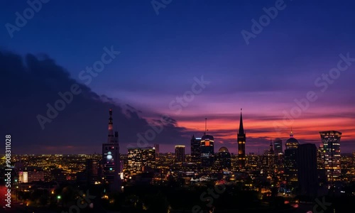 Wallpaper Mural City Lights Under Twilight Sky: A mesmerizing cityscape bathed in the ethereal glow of twilight, with a dramatic cloud formation casting long shadows over the urban landscape. The vibrant hues of the  Torontodigital.ca