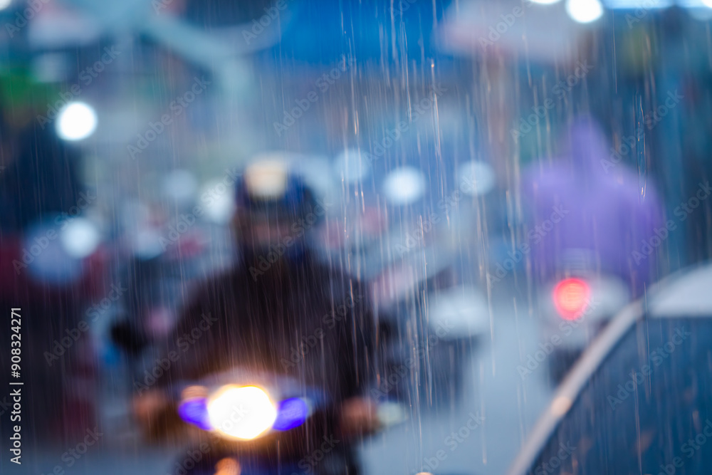 Fototapeta premium A blurry image of a rainy street with a man on a motorcycle and a woman in a purple jacket