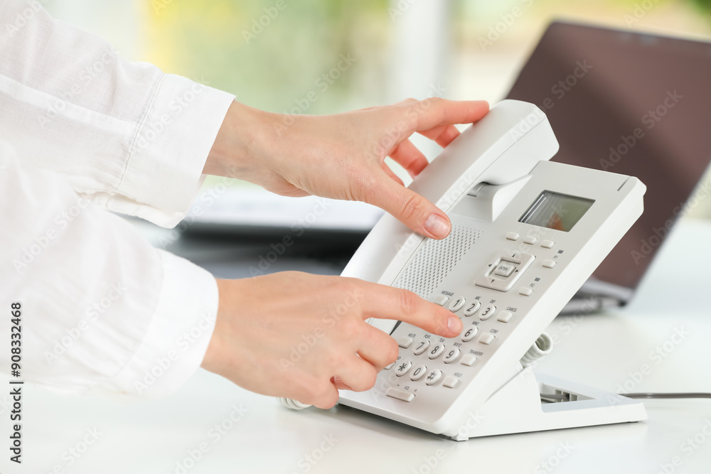 Assistant dialing number on telephone at white table, closeup Assistant dialing number on telephone at white table, closeup