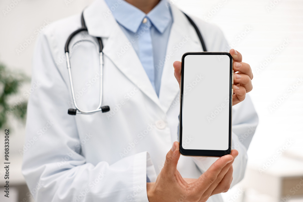 Doctor showing smartphone with blank screen in hospital, selective focus Doctor showing smartphone with blank screen in hospital, selective focus
