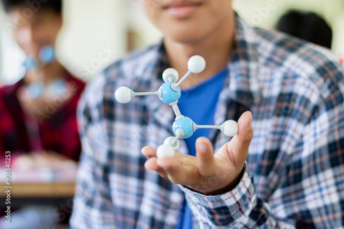 Students are studying simulate shape of covalent molecules by connecting molecular function shapes on the desk in Chemistry lesson, soft focus.