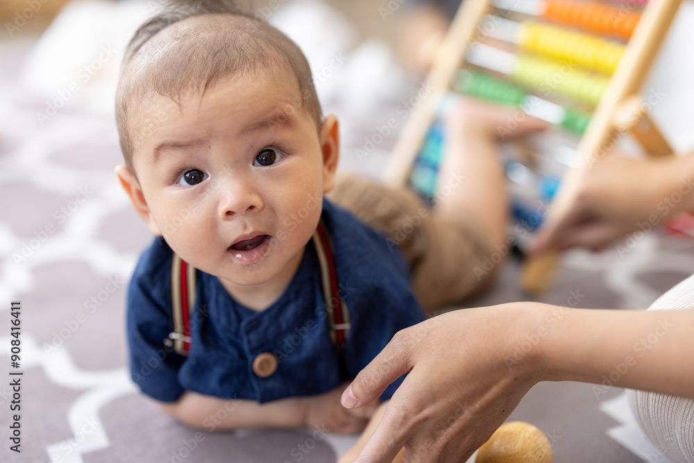 Asian newborn baby boy lying on the floor playing with colorful kid toys. Happy baby boy in kindergarten or daycare. Child playing with colorful educational toys in preschool. Kid play in playground. Asian newborn baby boy lying on the floor playing with colorful kid toys. Happy baby boy in kindergarten or daycare. Child playing with colorful educational toys in preschool. Kid play in playground.