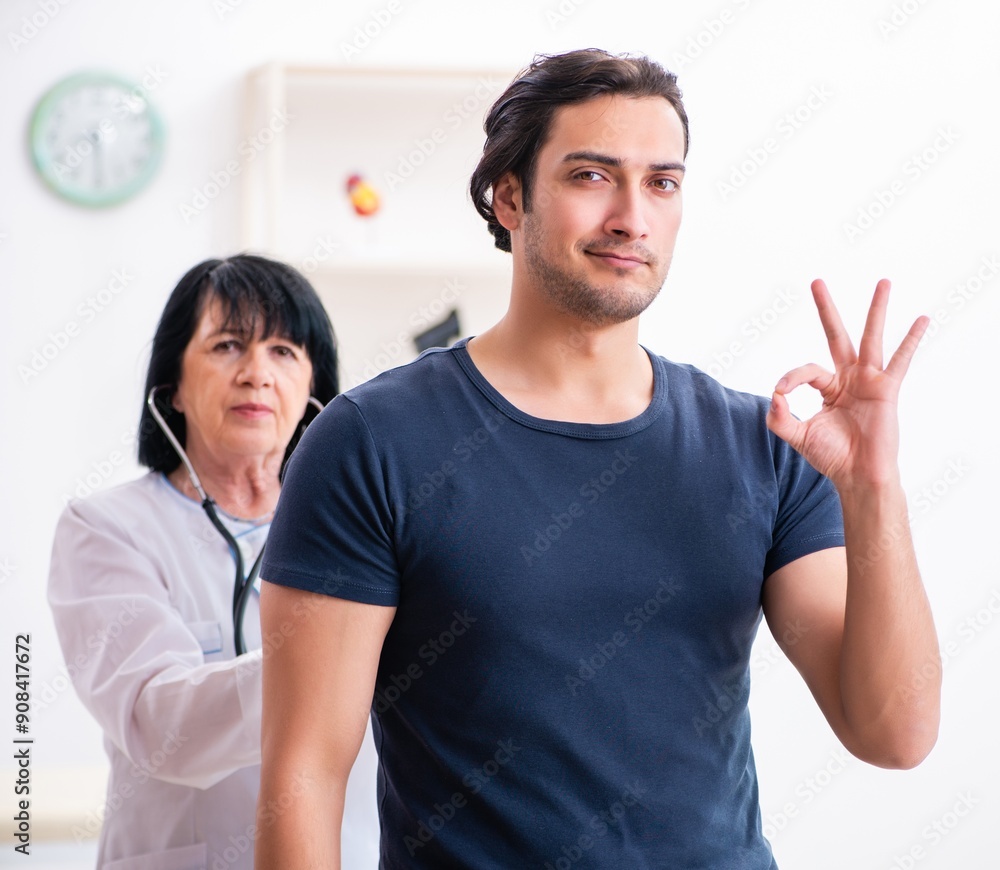 Young male patient visiting aged female doctor Young male patient visiting aged female doctor