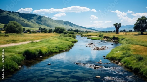 Tranquil rural landscape with houses by a flowing river under a bright blue sky.