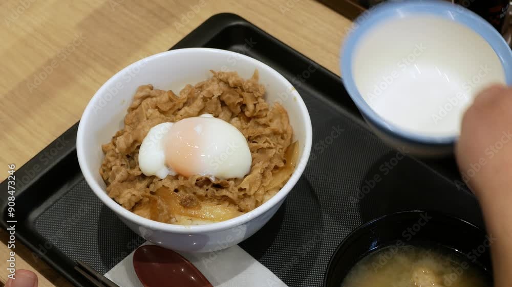 using chopsticks gently pierce the surface of raw egg which placed on beef rice or gyudon japanese food.creamy yolk embrace the succulent beef sliced using chopsticks gently pierce the surface of raw egg which placed on beef rice or gyudon japanese food.creamy yolk embrace the succulent beef sliced