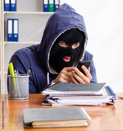 Male thief in balaclava in the office