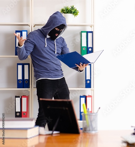 Male thief in balaclava in the office