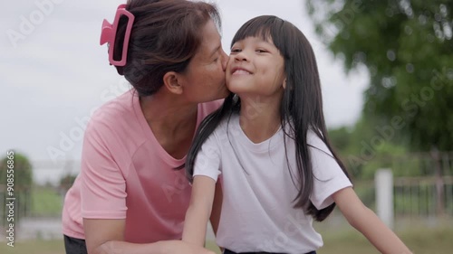 Hand-held portrait video of Thai mother and daughter, beautiful and cute face, mother teaching daughter to ride a bike and play in the outdoor field happily and joyfully, Mother's Day concept