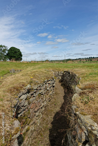 Looking down the narrow inner Passage or Souterrain of the Carlungie Earth House, with its layered stone built walls. photo