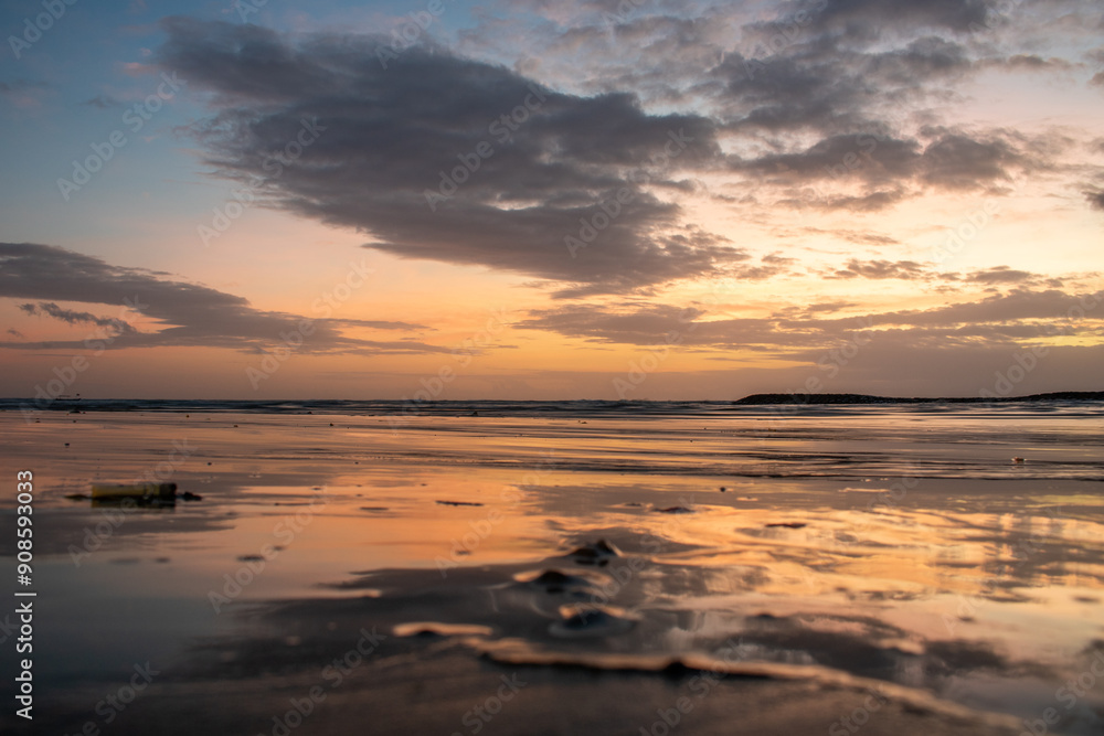 Water landscape, gently sloping sandy beach with light waves. The incredible sky is reflected in the wet sand in the romantic sunset in Kuta, Bali, Indonesia Water landscape, gently sloping sandy beach with light waves. The incredible sky is reflected in the wet sand in the romantic sunset in Kuta, Bali, Indonesia