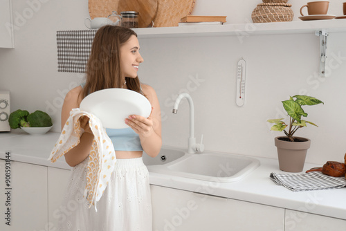 Young woman wiping plate ne...