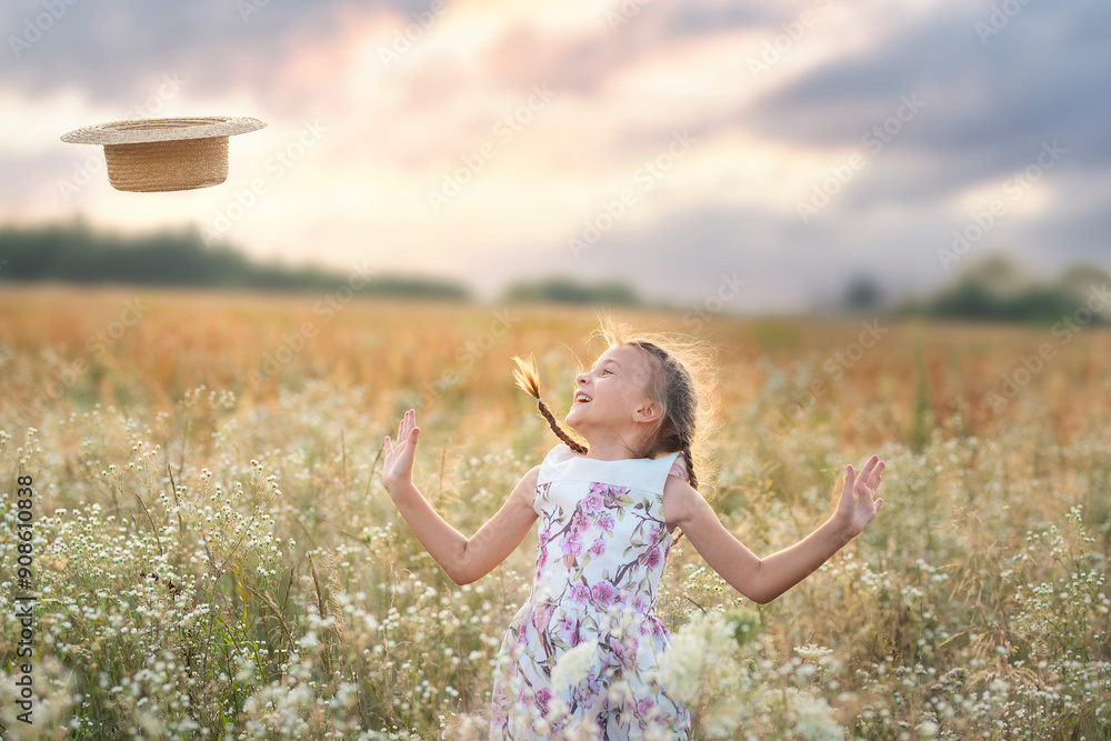 Φωτογραφία A mischievous child girl in a dress with pigtails and a straw hat in her hands j