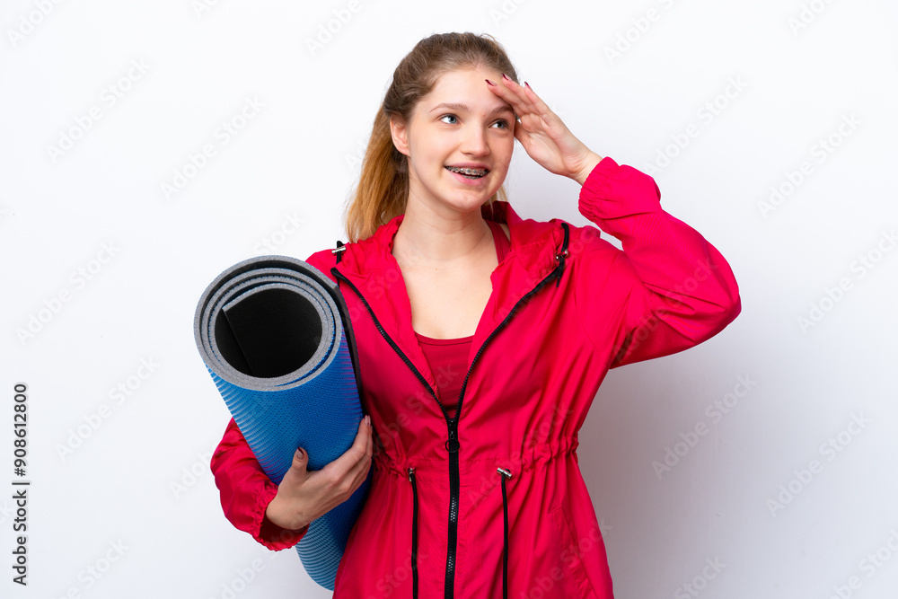 Teenager girl going to yoga classes while holding a mat isolated on white bakcground smiling a lot Teenager girl going to yoga classes while holding a mat isolated on white bakcground smiling a lot