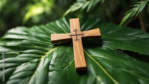 Wooden christian cross on green palm leaf background, top view. photo