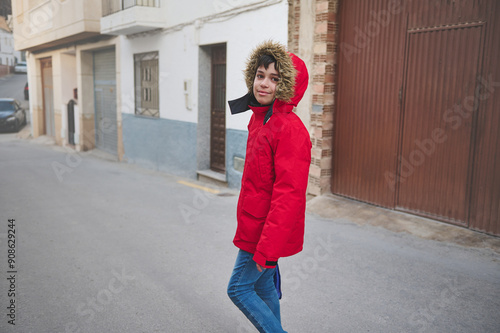 Smiling young person in red winter jacket walking on street in cozy neighborhood