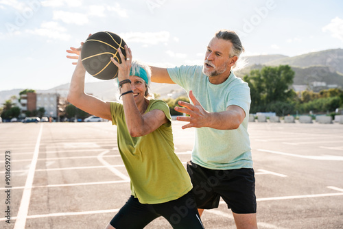 Beautiful happy senior couple playing basketball and having fun - Mature married couple in love bonding outdoors and doing sport together, concepts about elderly lifestyle, relationship and quality of photo