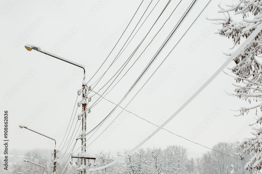 Poles and wires are covered with snow and ice. The power line was covered with snow. Concept of electricity problems and outages during winter snow storms in the countryside. Poles and wires are covered with snow and ice. The power line was covered with snow. Concept of electricity problems and outages during winter snow storms in the countryside.