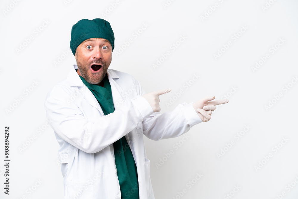 Middle age surgeon in green uniform isolated on white background surprised and pointing side Middle age surgeon in green uniform isolated on white background surprised and pointing side