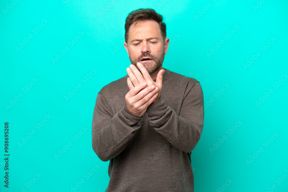 Middle age caucasian man isolated on blue background suffering from pain in hands Middle age caucasian man isolated on blue background suffering from pain in hands
