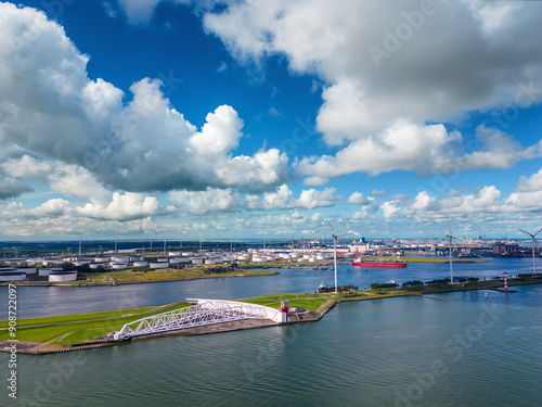 Aerial view of the Maeslant Barrier/Maeslant Kering at the port of Rotterdam with ships, oil terminals, and wind turbines.