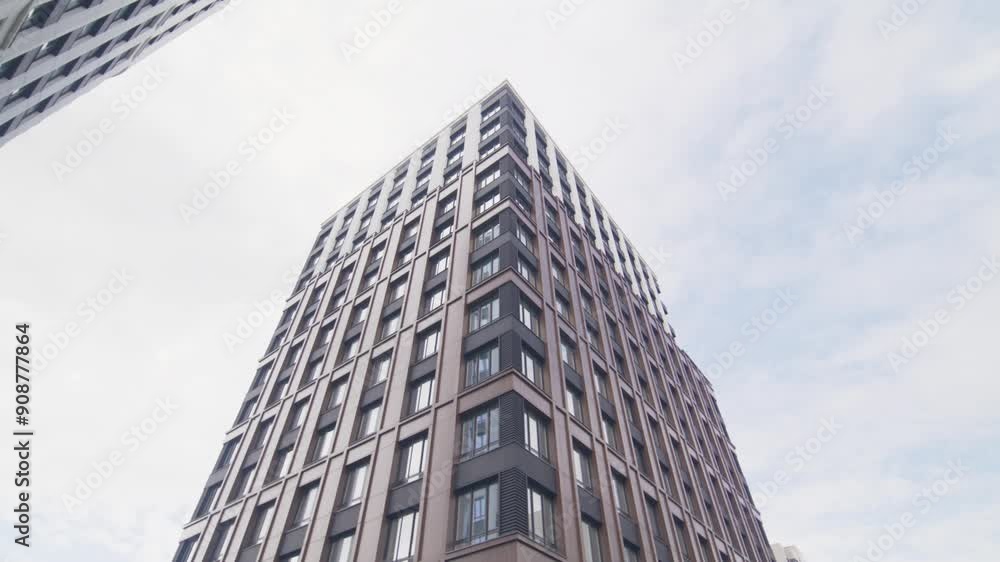 Plot with green lawn and trees located near tall residential building. Modern office building stretching to cloudy sky low angle shot Plot with green lawn and trees located near tall residential building. Modern office building stretching to cloudy sky low angle shot
