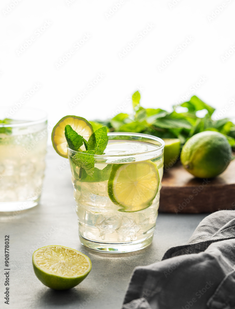 Two glasses lime mojito with mint and ice. Refreshing citrus cocktail on a light background. Summer cold lemonade drinks concept. Two glasses lime mojito with mint and ice. Refreshing citrus cocktail on a light background. Summer cold lemonade drinks concept.
