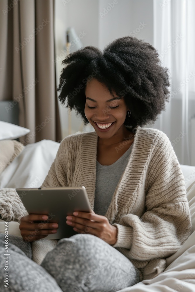 A woman is sitting on a bed and smiling while holding a tablet. She is enjoying her time and is likely using the tablet for entertainment or communication A woman is sitting on a bed and smiling while holding a tablet. She is enjoying her time and is likely using the tablet for entertainment or communication