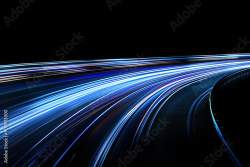 Long exposure photo of blue light trails on a curved road at night