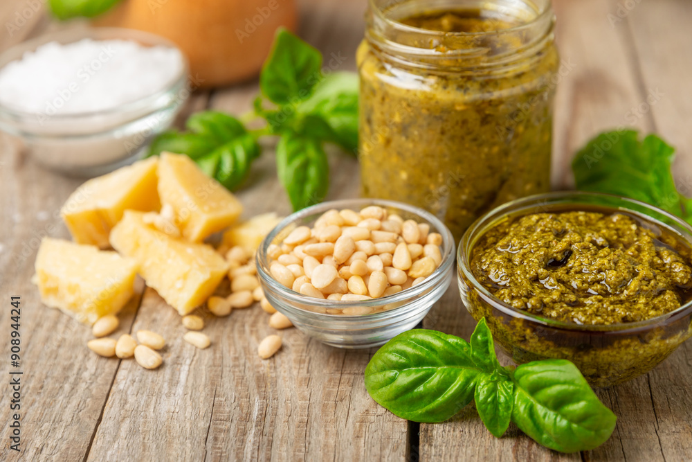 Pesto. Italian basil pesto sauce on a textured wooden background. Ingredient for pesto sauce: fresh basil, pine nuts, Parmesan cheese and olive oil. Space for text.Copy space. Pesto. Italian basil pesto sauce on a textured wooden background. Ingredient for pesto sauce: fresh basil, pine nuts, Parmesan cheese and olive oil. Space for text.Copy space.