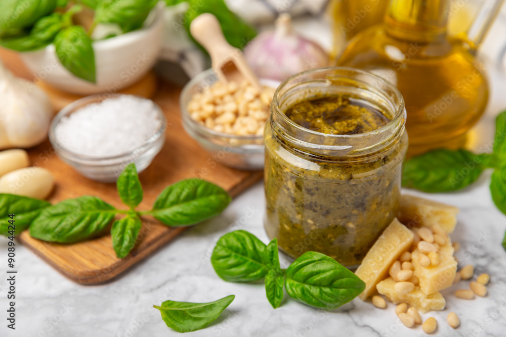 Pesto. Italian basil pesto sauce on a textured wooden background. Ingredient for pesto sauce: fresh basil, pine nuts, Parmesan cheese and olive oil. Space for text.Copy space. Pesto. Italian basil pesto sauce on a textured wooden background. Ingredient for pesto sauce: fresh basil, pine nuts, Parmesan cheese and olive oil. Space for text.Copy space.