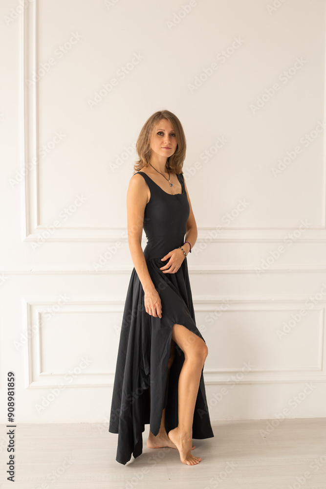 Stylish woman in a black dress near white wall at home Stylish woman in a black dress near white wall at home