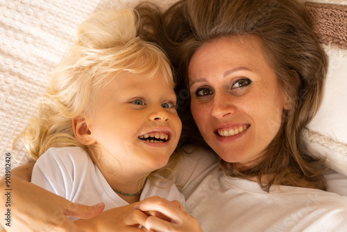 Mother and her little son baby boy hugging lying on bed at home having good time. Motherhood, affection