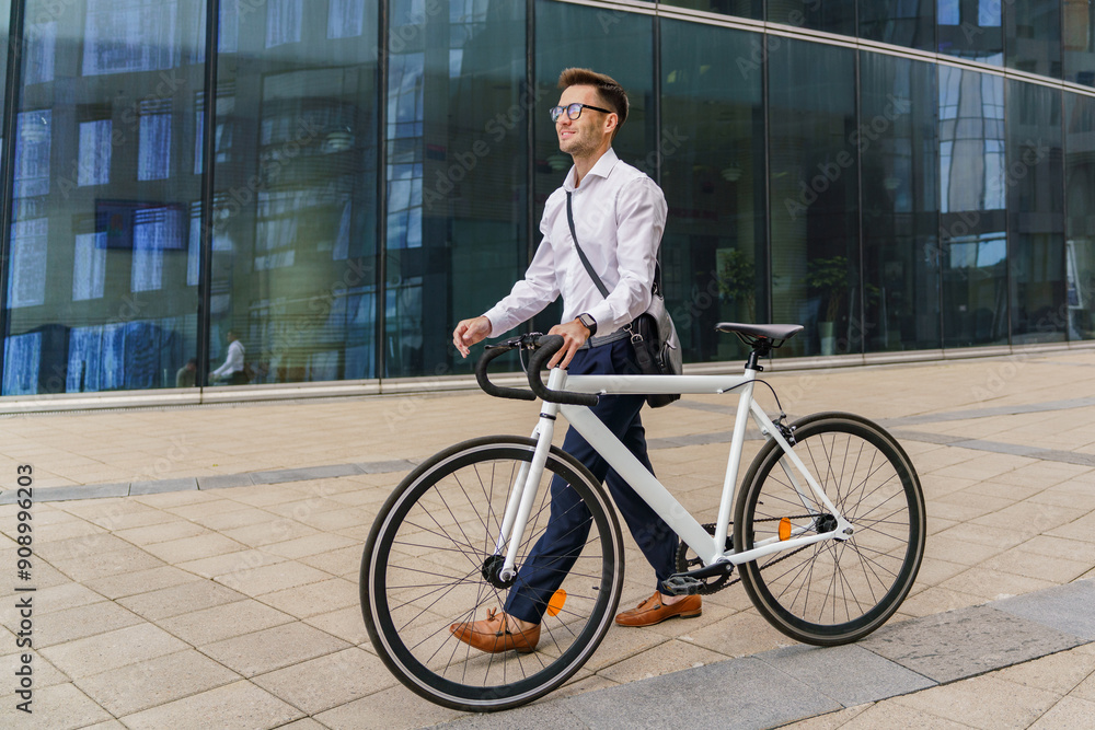 A professional man walks his bicycle beside a modern glass office building, exuding confidence and style. A professional man walks his bicycle beside a modern glass office building, exuding confidence and style.